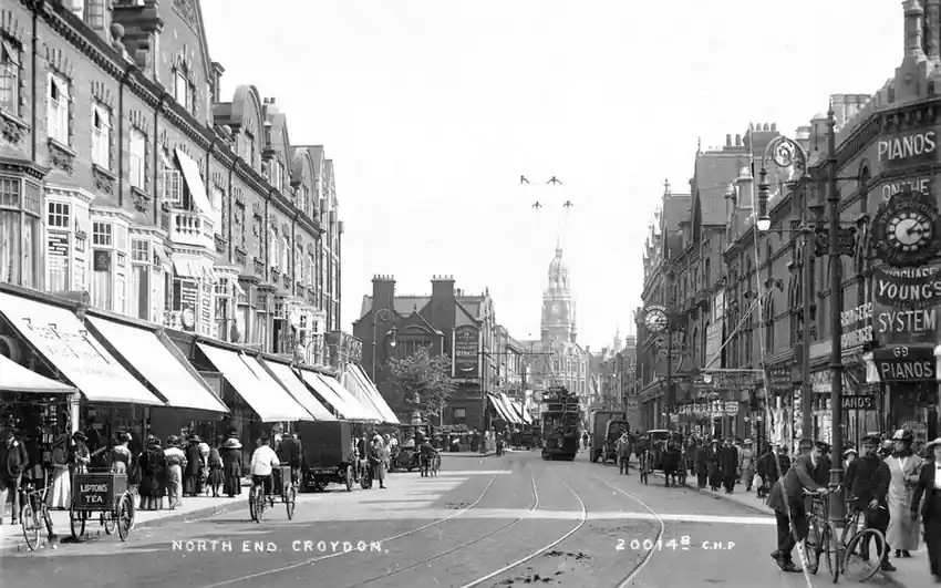 A black-and-white postcard photograph of a busy town high street